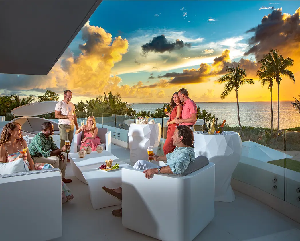 people in the villa overlooking the ocean during sunset